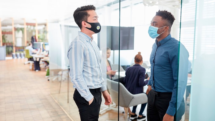 Zwei Männer mit Masken stehen in einer Tür und blicken sich an