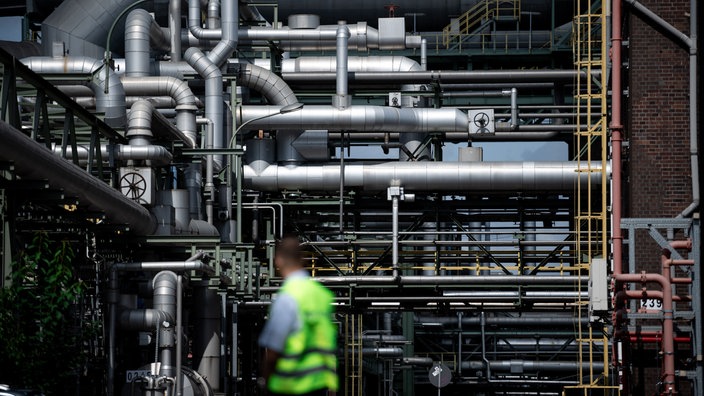 Rohre auf dem Gelände des Evonik-Chemieparks in Marl, davor ein Arbeiter