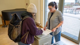 Eine junge Wählerin wirft ihren Stimmzettel in die Wahlurne 