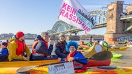 Demonstranten fahren mit Kanus und Kayaks über den Rhein