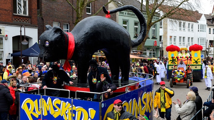 Das Bild zeigt den Kater "Rumskedi" als Karnevalswagen. Der schwarze Kater mit dem Buckel ist die Symbolfigur des Beckumer Karneval.