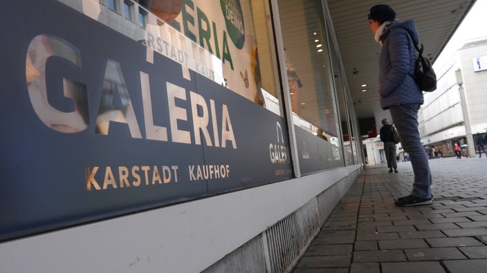 Eine Passantin betrachtet ein Schaufenster von Karstadt Kaufhof in Bielefeld.