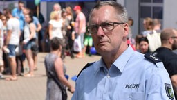 Ein Polizist mit grauen Haaren und Brille schaut kritisch in die Kamera