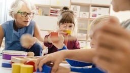 Kinder und Erzieherin spielen mit Musikinstrumenten