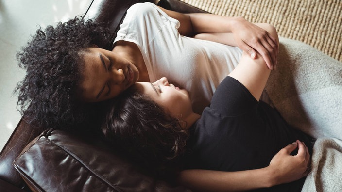 Ein Pärchen schläft kuschelnd auf der Couch