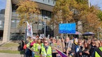 Menschen halten bunte Plakate bei einer Demonstration vor dem Düsseldorfer Landtag