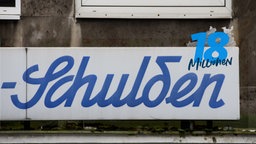 Ladenlokal-Schild in geschwungener Schrift auf dem "Schulden" steht