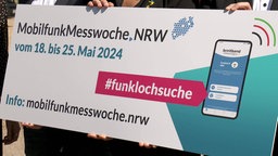 Mona Neubaur und andere halten ein Schild in Händen