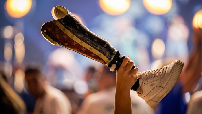 Eröffnungsfeier der Invictus Games in Düsseldorf: Eine Teilnehmerin, die amerikanische Soldatin Annika Hutsler, reckt ihre Beinprothese in die Höhe, zu sehen ist nur die Prothese mit Schuh, die von einer Hand hochgehalten wird.