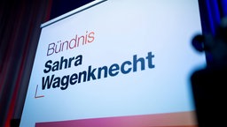 Logo mit der Aufschrift "Bündnis Sahra Wagenknecht" wird auf eine Leinwand projiziert. 