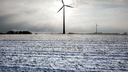 Zwei Windraeder drehen sich am Rande von schneebedeckten Feldern in Bottrop-Kirchhellen.