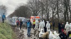 Aktivisten stehen in Lützerath auf einer Straße neben einem Notarztwagen