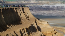 Teilnehmer des Dorfspaziergangs in Lützerath stehen an der Kante des Tagebaus Garzweiler II. 