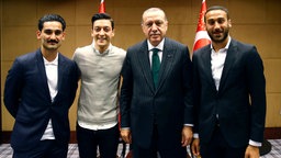 Der Staatspräsident der Türkei steht zusammen mit den Premier League Fußballspielern Ilkay Gündogan, Mesut Özil und Cenk Tosun.