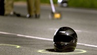 Nach einem schweren Unfall liegt ein Motorradhelm auf der Straße