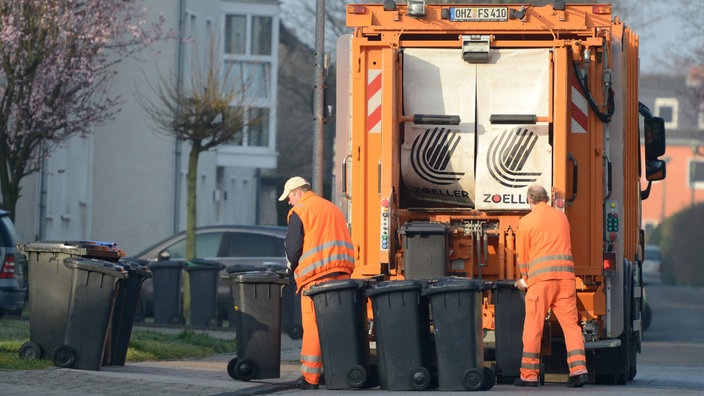 Zwei Männer von der Müllabfuhr entleeren Mülltonnen 