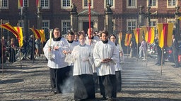 Menschen in Kirchengewändern gehen über die Straße