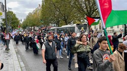 Demonstrierende einer Pro-Palästina-Demo in Aachen mit Schildern und Palästina-Fahnen.