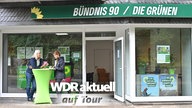 Zwei Menschen unterhalten sich vor einem Büro der Partei Bündnis 90 / Die Grünen