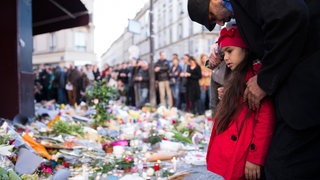 Viele Menschen legen Blumen vor dem Cafè Carillon ab