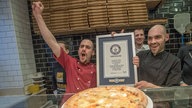 Die Pizzabäcker Mirko (l) und Andrea vom Restaurant Vadoli jubeln über ihren erfolgreichen Weltrekordversuch mit 111 Käsesorten auf einer Pizza.