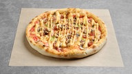  Pizza mit dünner Wurst, Jalapeno und Champignon, belegt mit Senf auf Pergamentpapier