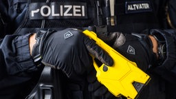 Ein Polizeibeamter hält einen Taser im Anschlag.