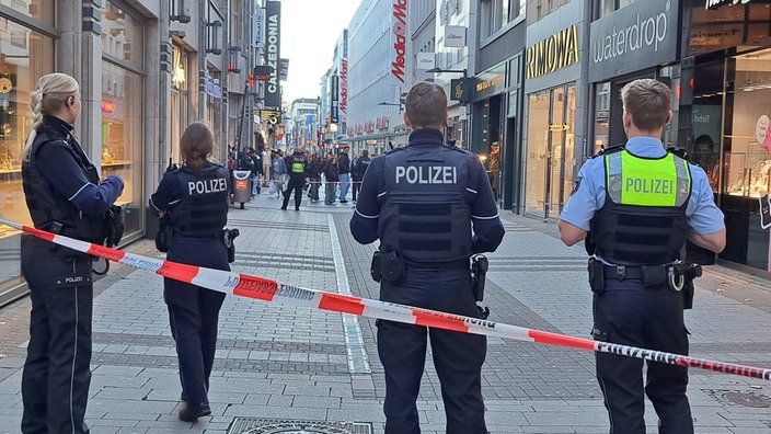 Vier Polizisten stehen in Köln vor einem Absperrband in der "Hohe Straße"