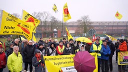 Menschen mit gelb leuchtenden Fahnen und Bannern demonstrieren vor dem Brennelemte-Zwischenlager