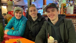 Luca, Lennart und Lasse schauen das deutsche Auftaktspiel auf dem Hagener Weihnachtsmarkt.