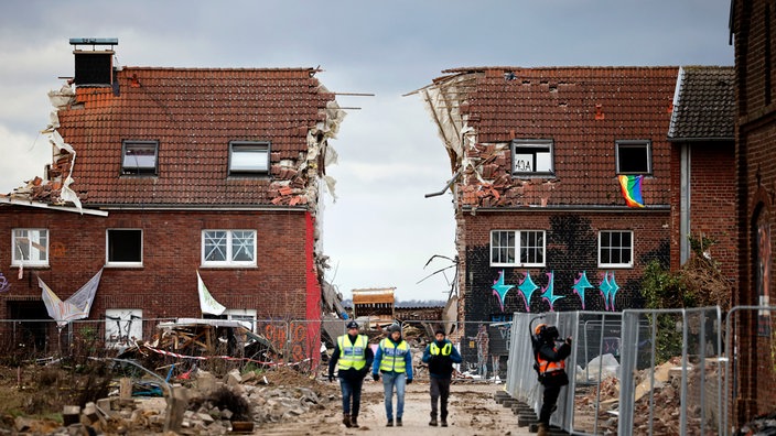 Ein abgerissenes Haus in Lützerath. Dazwischen eine große Lücke und mehrere Polizisten.