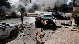 Männer versuchen, nach den Raketenangriffen aus dem Gaza-Streifen brennende Autos zu löschen.