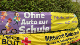 Ein Banner in gelb und lila mit dem Hinweis "Ohne Auto zur Schule"