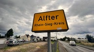 Ortsschild von Alfter von vorne, mit bewölktem Himmel im Hintergrund