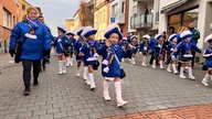 Zu sehen ist eine Kindergruppe, die durch die Straßen ziehen. 