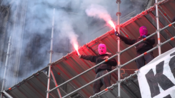 Aktivisten mit pinkfarbenen Sturmhaben zünden Pyrotechnik 