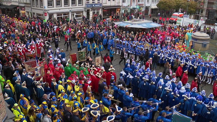 Viele Vereine in bunten Farben ziehen auf einem Platz und stellen sich dort auf