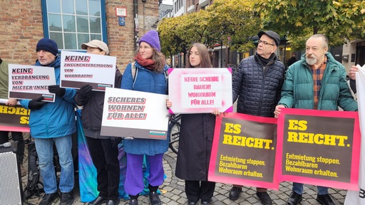 Mehrere Menschen nebeneinander mit verschiedenen Protestplakaten