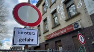 Zu sehen ist ein Warnschild vor dem einsturzgefährdetem Haus.