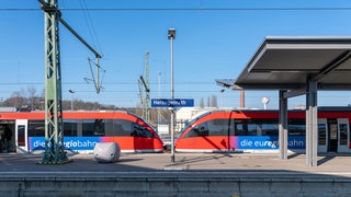 Es sind zwei rote Züge der Euregio-Bahn an einem Bahnsteig des Bahnhofs Herzogenrath zu sehen.