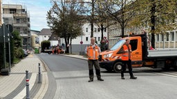 Eine Absperrung an einer Straße in Erkelenz: Zwei Menschen in orangenen Warnwesten