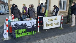 Auf dem Foto sind acht Personen, die hinter Plakaten mit Aufschriften wie "Stoppt Braunkohle!" stehen.