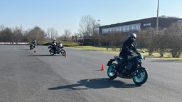 Motorradfahrer üben Slalom.