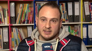 Ein Mann mit Hoodie vor einem Bücherregel