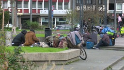 Obdachlose auf dem Krefelder Theaterplatz, daneben viele Säcke und ein Fahrrad mit Decken