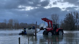 Ein Traktor bringt einen Kanister mit Milch zu dem Ponton-Boot des THW.