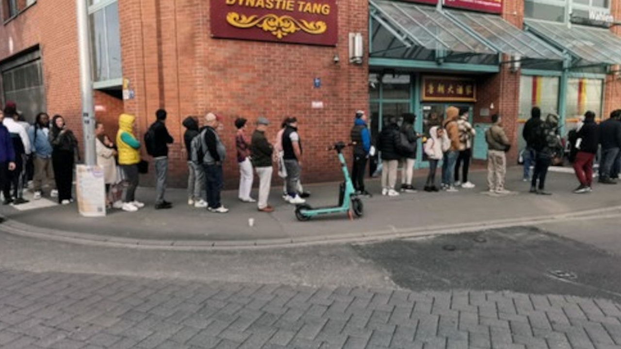 Eine Menschenschlange geht um eine Straßenecke.