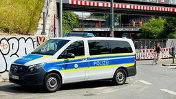 Man sieht ein Polizeiauto vor einem Bahnhof