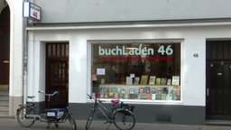 Fahrräder stehen vor dem Schaufenster des Buchladens 46. In der Auslage stehen unterschiedliche Bücher.