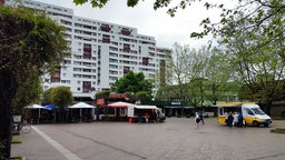 Auf dem Foto ist ein Marktplatz mit zwei Ständen darauf, dahinter ist eine Dönerbude.